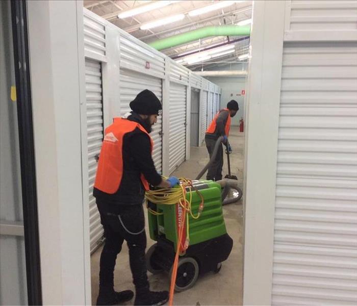 Two SERVPRO Team members extracting water from flooring.